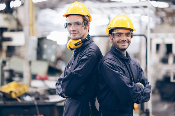 istock technician and partnership smile and lokking camera at machine in factory 1219936328
