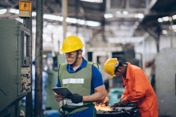 istock profession technician engineer operate heavy machine to automated CNC in factory, worker with check list 1219936378