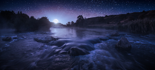 Beautiful starry night above the river in a light of rising moon