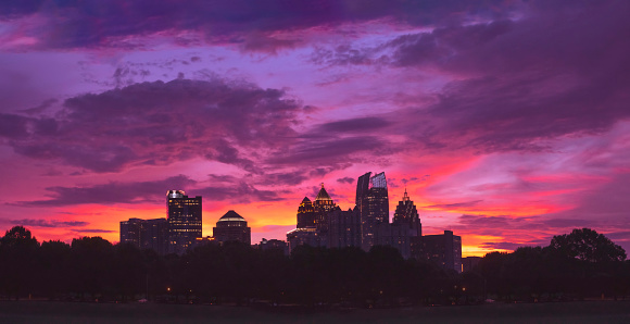 Sunset view of midtown Atlanta - the city of trees - peeking thru the lush tree canopy of Piedmont Park at sunset.