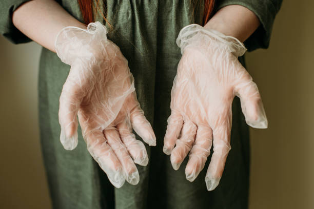 We protect children from the virus with medical gloves Red-haired girl in medical gloves on a plain background. latex stock pictures, royalty-free photos & images