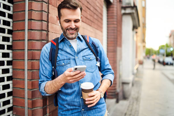 istock Man using phone while out in the city with coffee 1219938436