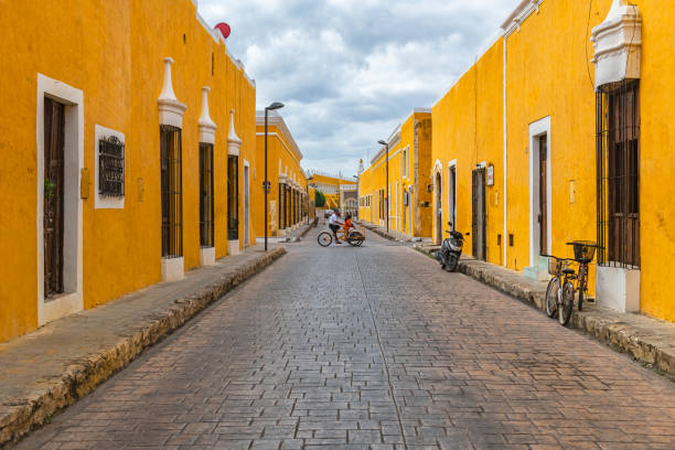 Tricycle Transport, Izamal, Mexico Cityscape with people on a Tricycle in the colorful yellow streets with colonial style architecture, Izamal, Mexico. valladolid mexico photos stock pictures, royalty-free photos & images