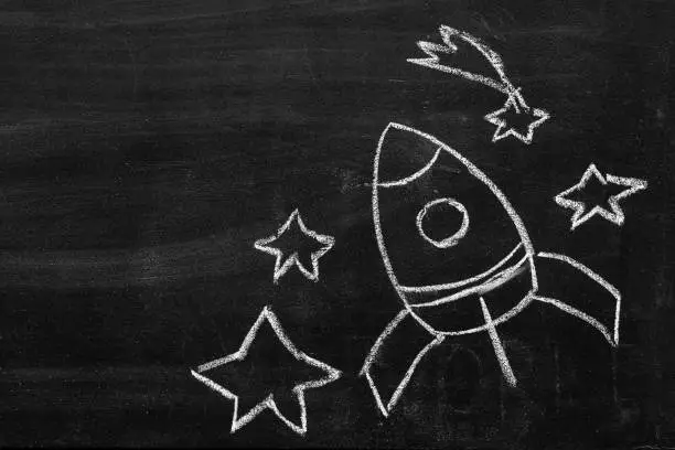 April 12 International Cosmonautics Aviation Day. Hand-drawn rocket, cosmonaut, comet, stars, infinite space. empty space for inscription. chalkboard, blackboard texture