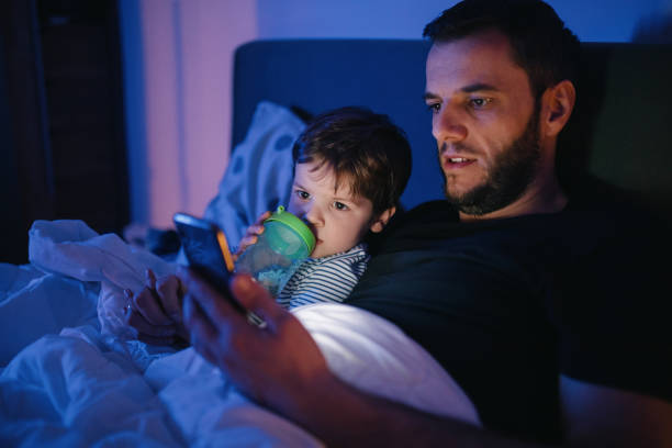 istock Father and son using phone, little boy drinking from sippy cup 1219940457
