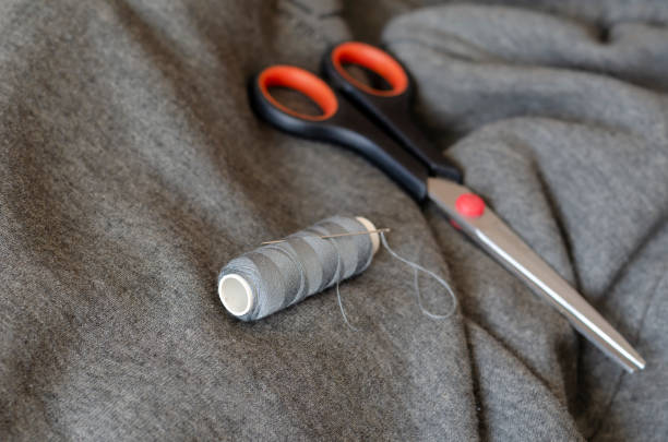 istock Spool of gray thread with a needle and scissors. 1219940725