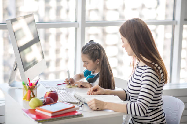 istock Dark-haired girl and her tutor sitting at the table doing homework 1219941060