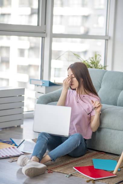 istock Young woman taking off glasses sitting on the floor. 1219941200
