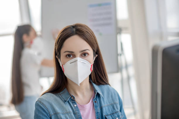 istock Dark-haired woman with brown eyes in a protective mask. 1219942614