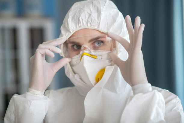 istock Woman in white workwear putting on protective eyewear 1219945289