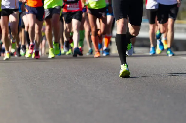 Legs of athletes running half marathon on the road