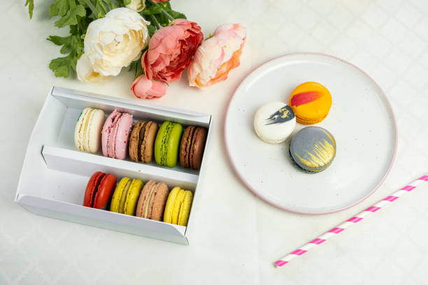 istock colorful modern macaroons in gift box and on plate for celebration romantic party birthday on white, pion flowers, satin ribbon top view 1219946768