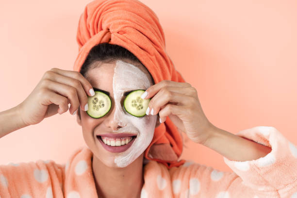 junge frau mit hautpflege spa tag zu hause - glückliches mädchen anwendung gurke gesichtsreiniger maske - gesunde schönheit saubere alternative behandlung und kosmetik produkte konzept - beautiful smiling vegetable calcium stock-fotos und bilder