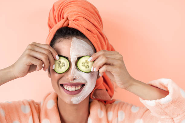 집에서 스킨 케어 스파 데이를 갖는 젊은 여성 - 오이 얼굴 클렌저 마스크를 적용하는 행복한 소녀 - 건강한 아름다움 깨끗한 대체 치료 및 화장품 제품 개념 - beautiful smiling vegetable calcium 뉴스 사진 이미지