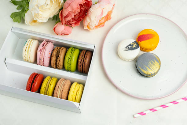 istock colorful modern macaroons in gift box and on plate for celebration romantic party birthday on white, pion flowers, satin ribbon top view 1219946807