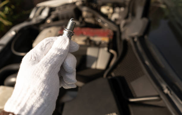 le mécanicien tient la nouvelle bougie d’allumage d’iridium avec la petite électrode pour une bonne et haute précision étincelle dans un état difficile, un boost élevé ou un rapport de carburant à air maigre. cette image pour une utilisation à - preventative maintenance photos et images de collection