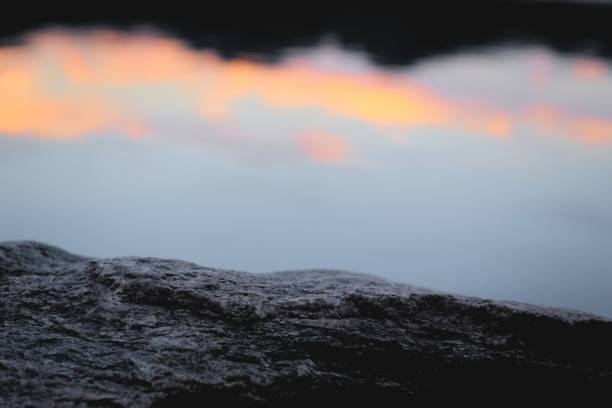 istock Calm, serene natural environment. Rock texture close up against twilight sky reflections on a lake. 1219947600