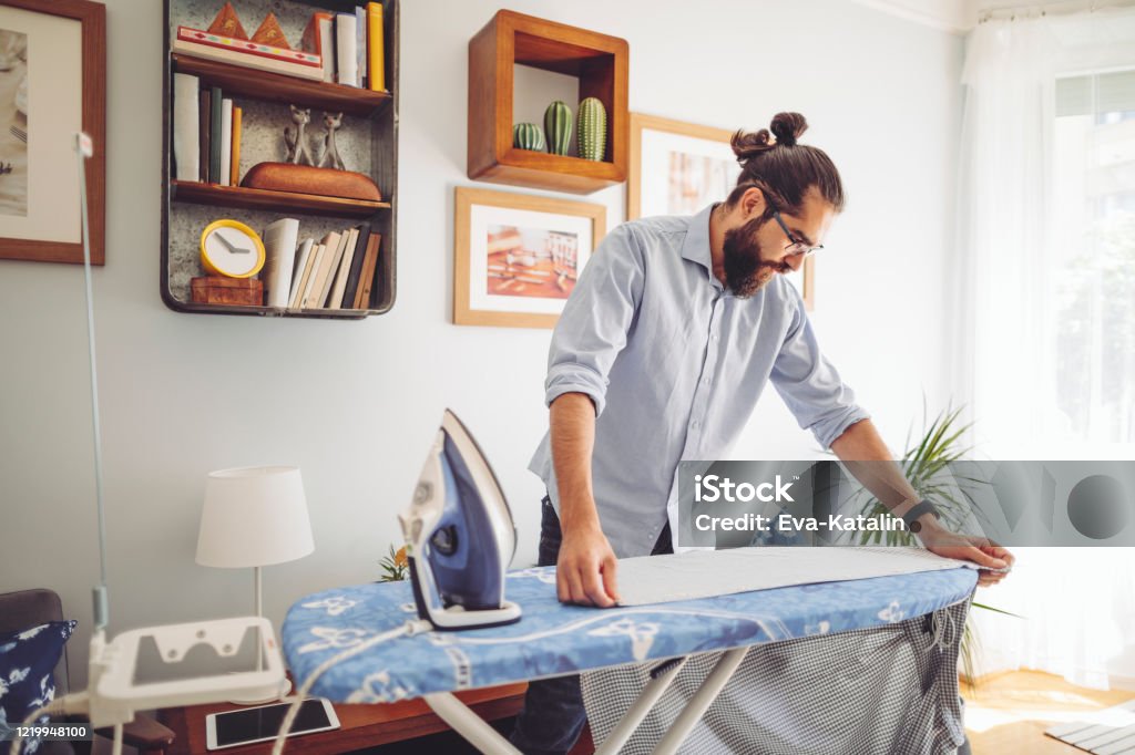 Young man ironing his shirt Iron - Appliance Stock Photo