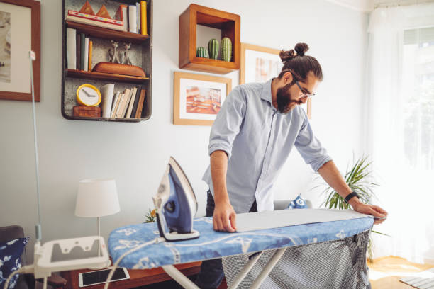 Young man ironing his shirt stock photo