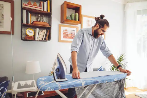 Young man ironing his shirt