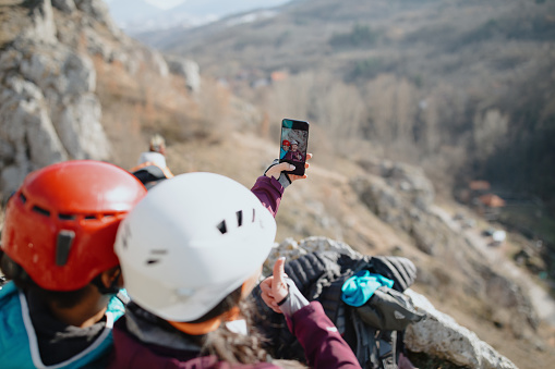 Two happy female climbers taking selfie on the top of the cliff