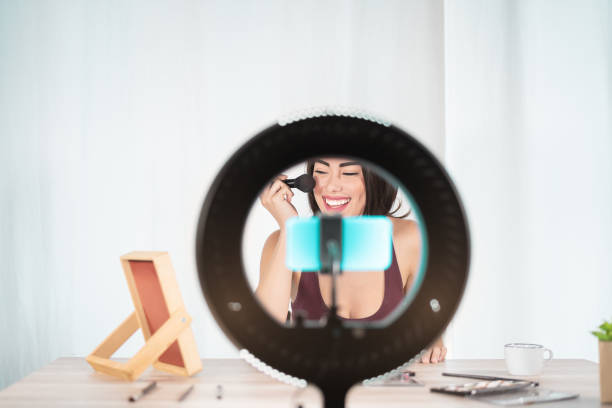 istock Young female vlogger doing makeup tutorial video for web channel at home - Happy influencer girl having fun filming with mobile smartphone - Social medial and millennial generation lifestyle concept 1219949035