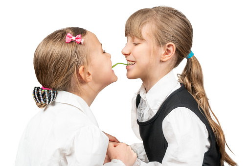 two sisters eating green onions together holding hands isolated on white background