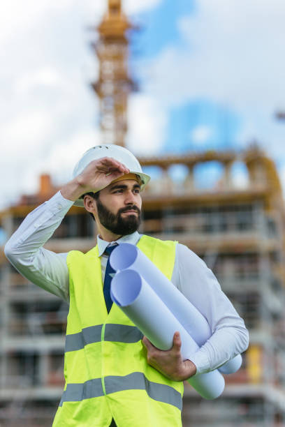 istock Handsome businessman holding blueprints and looking away 1219951794