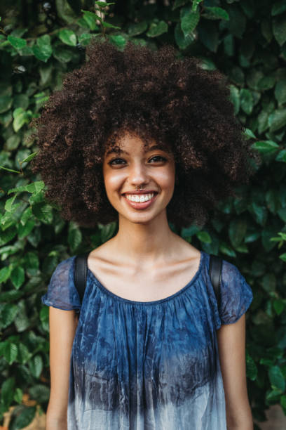 Portrait of a young woman with afro hair - Millennial with a green wall of leaves behind her Portrait of a young woman with afro hair - Millennial with a green wall of leaves behind her septum piercing stock pictures, royalty-free photos & images