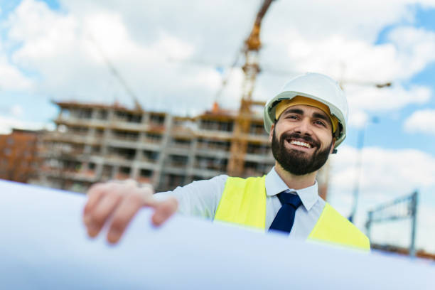 istock Handsome construction manager holding blueprint and smiling 1219951960