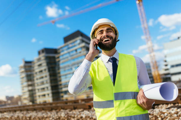 istock Happy architect holding blueprint and talking on mobile phone 1219952258