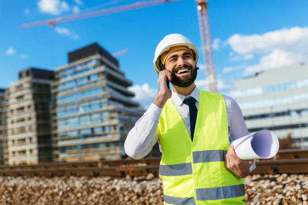 istock Happy engineer holding blueprint and talking on mobile phone 1219952312