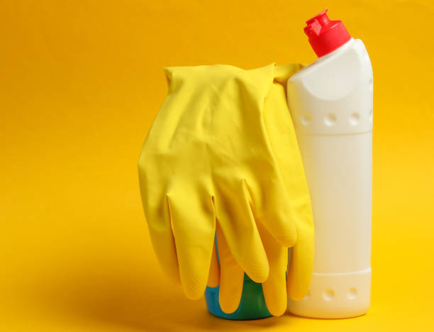 istock Cleaning concept. Detergent bottles, gloves on yellow background 1219952437