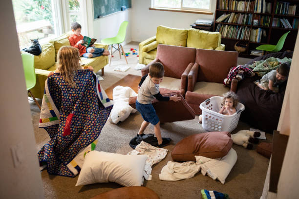 Kids Play and Imagine In Messy Living Room Toys, blankets, and disarranged furniture clutter a living room as kids play at home.  Normal routine or part of social distancing at home. cluttered photos stock pictures, royalty-free photos & images