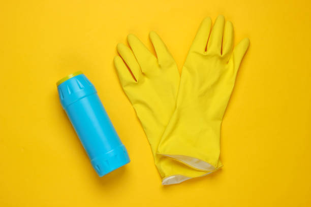 istock Ready for cleaning! Housework concept. Detergent bottle, gloves on yellow background. Top view 1219954347