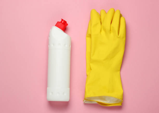 istock Ready for cleaning! Housework concept. Detergent bottle, gloves on pink pastel background. Top view 1219954426