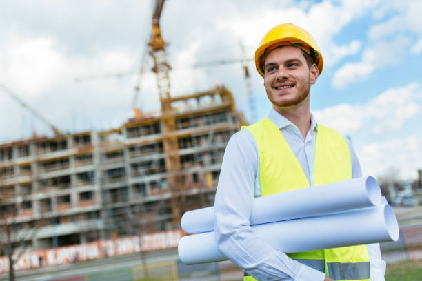 istock Young construction manager holding blueprints and smiling 1219954771