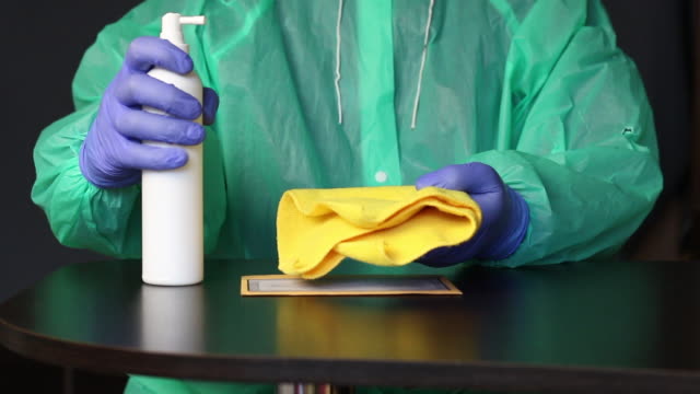 Delivery of correspondence during a pandemic. A man in rubber gloves and a raincoat treats the letter with an antiseptic and wipes it with a napkin. Symbol of the fight against the pandemic.