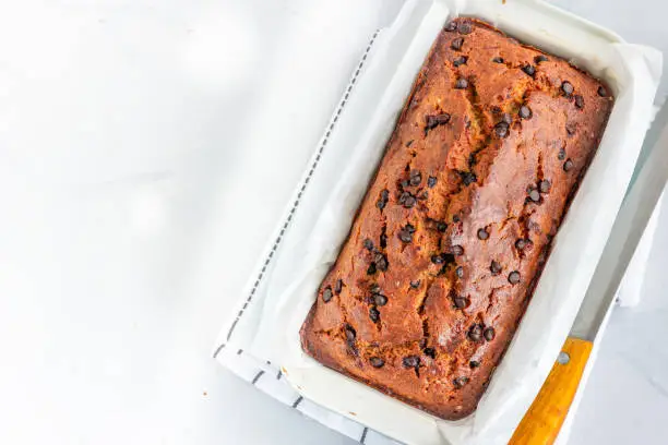 Banana Bread with Chocolate Chips on a Wooden Board with Knife, Flat Lay, Top Down Photo