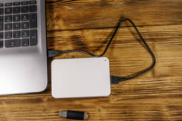 istock External HDD connected to laptop computer and USB flash drive on a wooden desk. Top view. Concept of data storage 1219959119