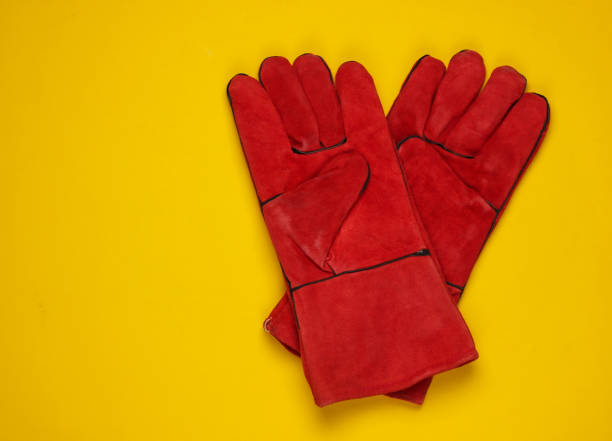istock Red work gloves on yellow background. Top view. 1219960499
