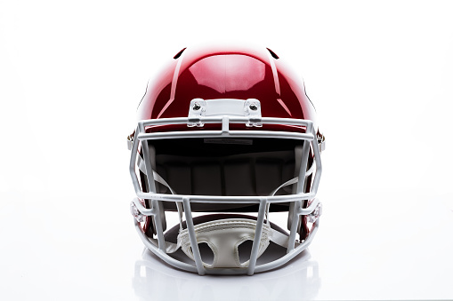 Red colored football helmet in front position on white background