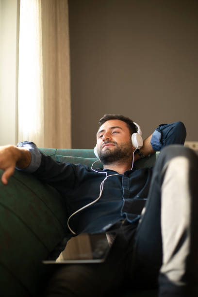 istock Man on his sofa listening to music with a tablet 1219963624