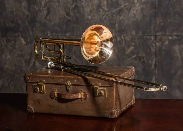 Photo of Musical instrument trombone lies on an old suitcase