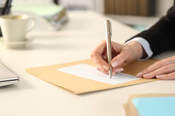 business woman hand filling out bank check at the office - endorsing business application form filling imagens e fotografias de stock