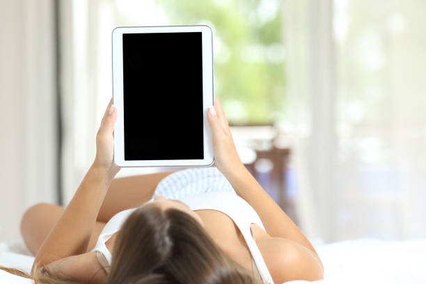 istock Woman showing blank tablet screen lying in bed 1219963955