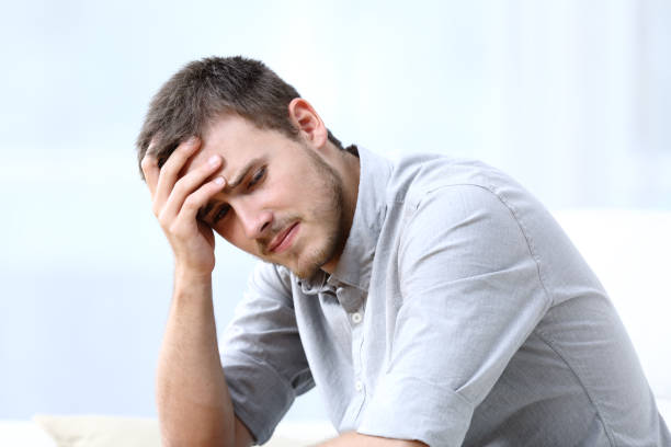 Sad worried man complaining on a couch at home