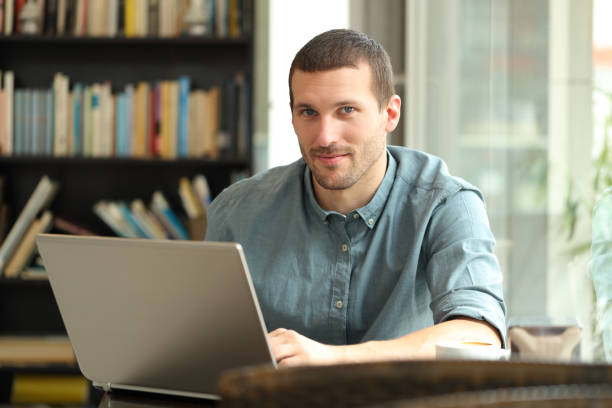 istock Man with laptop looking camera on a coffee shop 1219965339