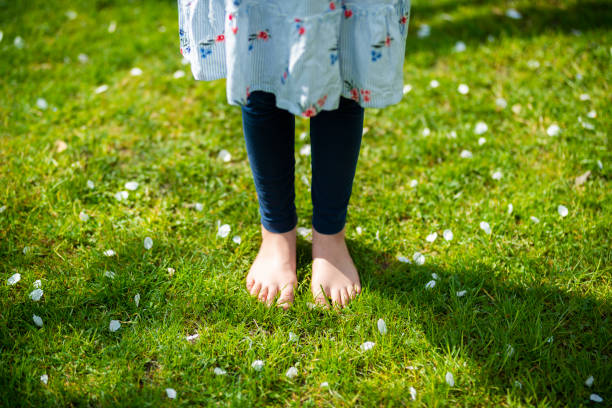Germany, young Girl stands in the green grass between apple blossoms.
