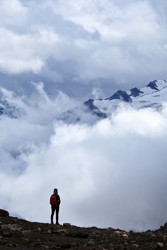 A silhouette of a hiker standing against dramatic storm clouds in a remote region of the Purcell Mountains near Invermere, British Columbia, Canada.